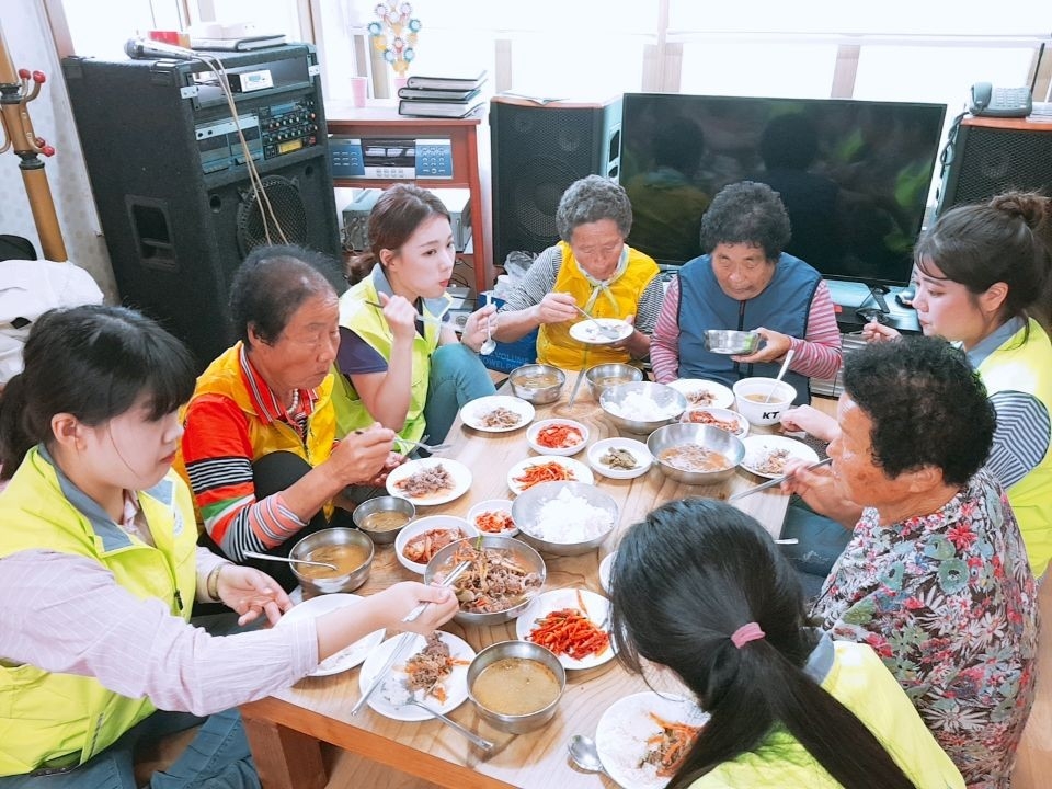 호산대학교 학생들이 봉사활동 후 마을 어르신들과 식사를 하고 있다.