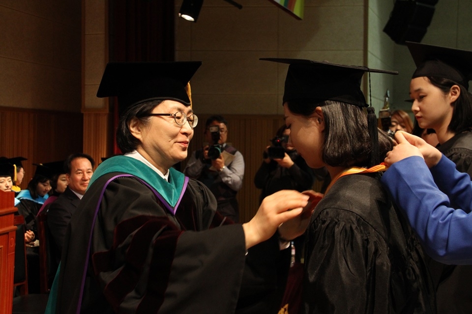 김희진 총장(왼쪽)이 졸업생에게 휘장을 걸어주며 축하를 했다.