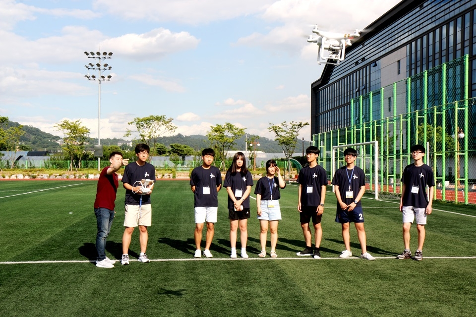 한국항공대 항공캠프에 참가한 학생들이 드론전문가로부터 설명을 들으며 직접 드론을 조종해보고 있다.[사진=한국항공대 제공]