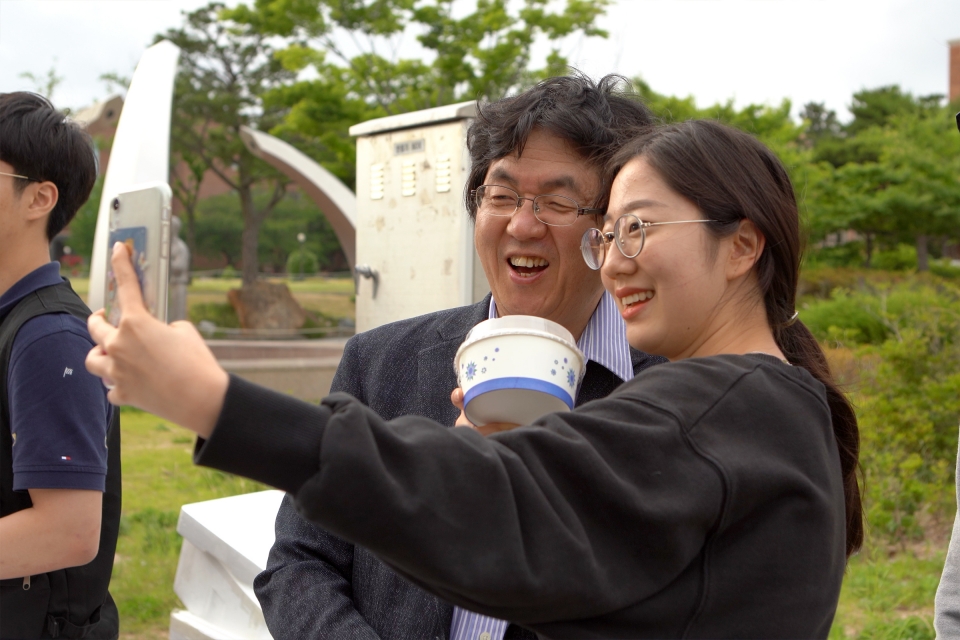 장순흥 총장의 기말고사 야식 이벤트에 참가한 한 학생이 컵밥을 들고 장 총장과 기념 촬영을 하고 있다.