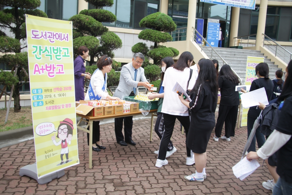 안규철 총장과 김영실 도서관장이 학생들에게 간식을 나눠주고 있다.