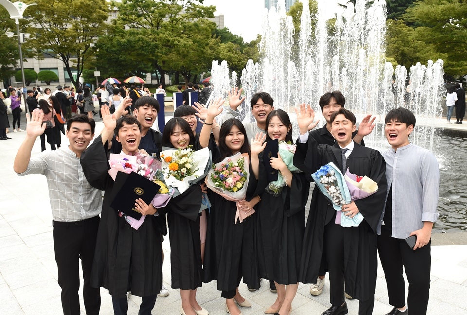 학위를 받은 학생들이 졸업을 축하하며 기념사진을 촬영하고 있다