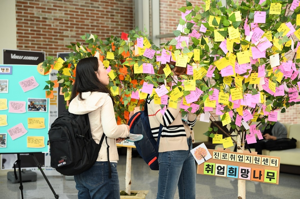 교내에 생긴 취업희망나무에 학생들이 소망을 담은 메모지를 걸고 있다.