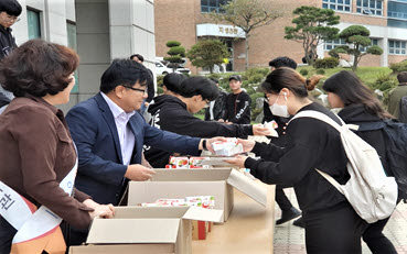 허남윤 오산대학교 총장직무대행과 남재경 도서관장 및 교직원들이 재학생들에게 간식을 나눠주고 있다.