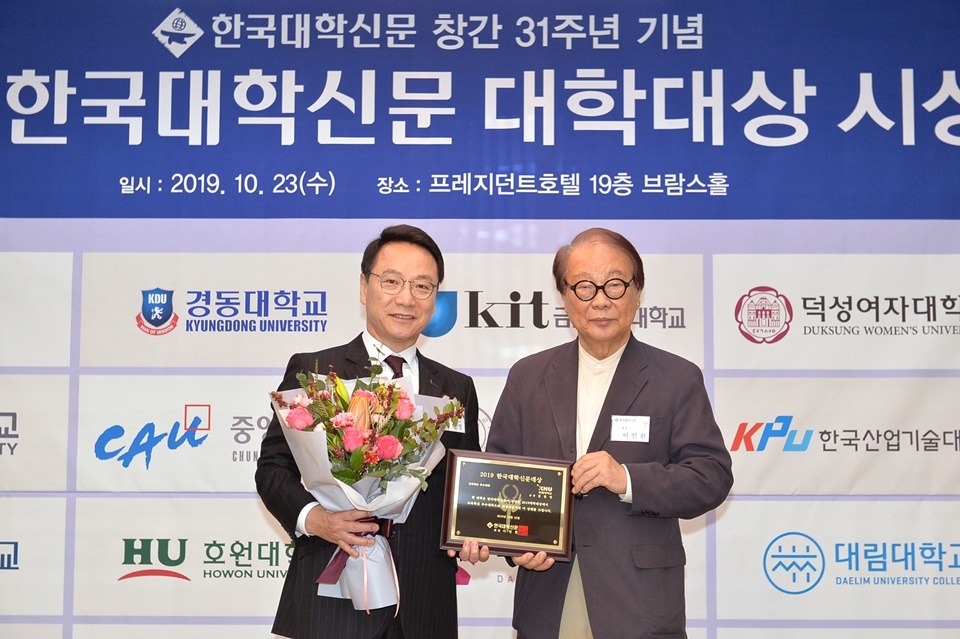 김헌영 강원대 총장(왼쪽)이 이인원 본지 회장으로부터 교육혁신 우수대학 상패와 꽃다발을 받고 기념촬영을 했다.