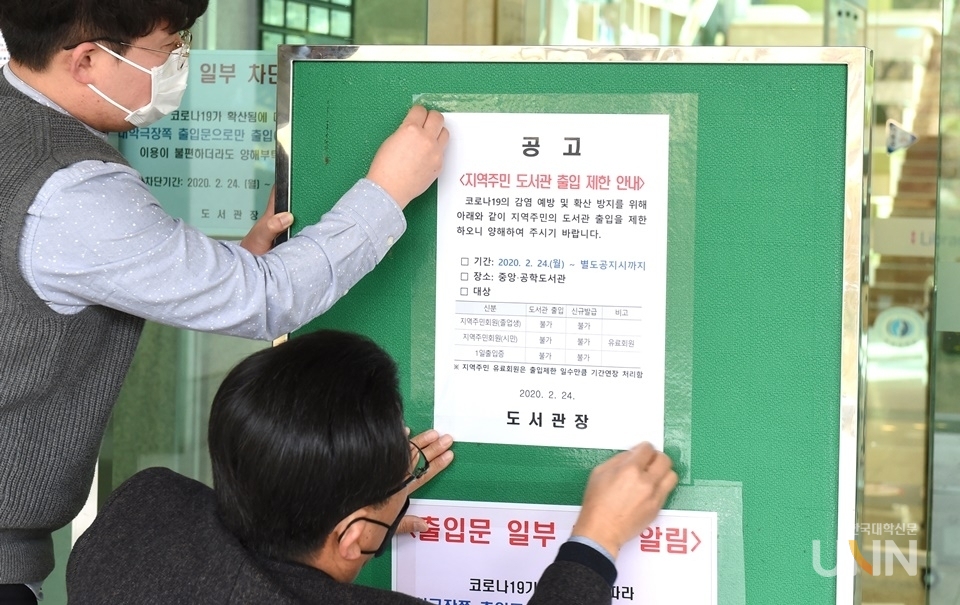 부경대 관계자들이 학교 시설물에 코로나19 관련 시설 폐쇄 안내문을 붙이고 있다. (한국대학신문 DB)