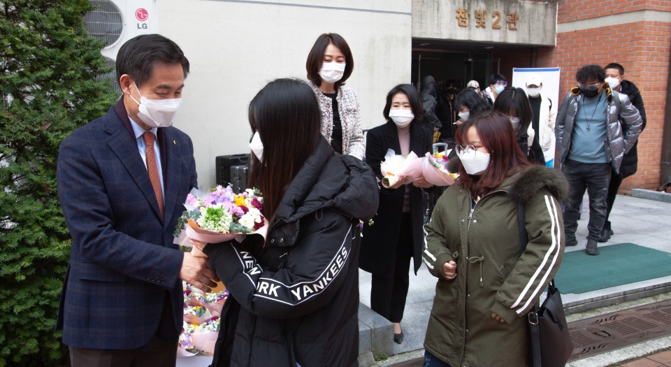 김동원 총장이 격리가 해제돼 생활관을 나오는 유학생들에게 꽃을 전하고 있다