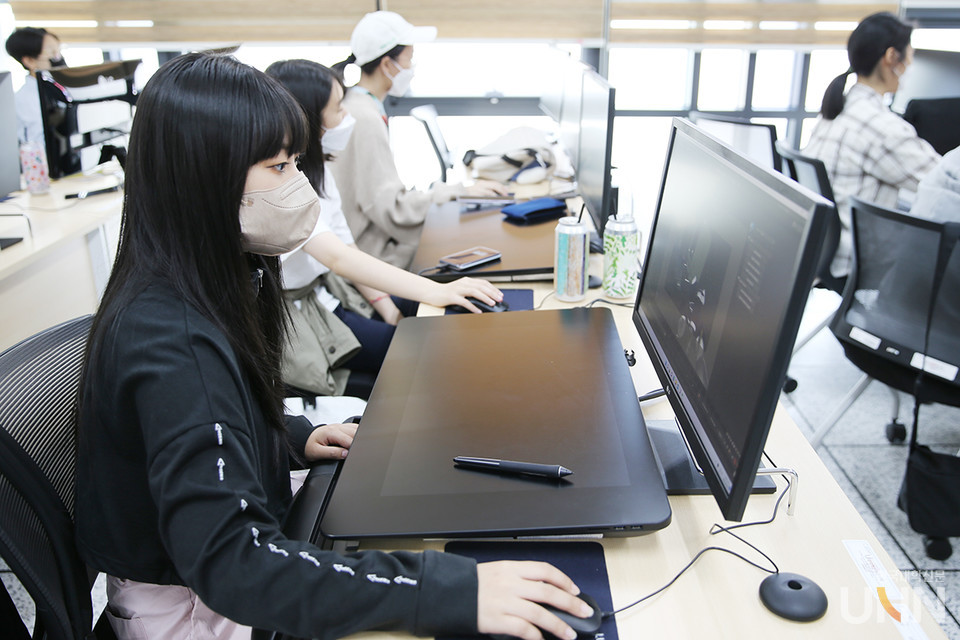 목원대 웹툰애니메이션게임대학 강의실에서 교수와 학생들이 컴퓨터로 3차원 그리기 실습을 하고 있다.