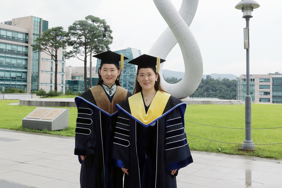 가천대에서 나란히 박사학위를 받은 중국인 쌍둥이 유학생 유하이징(왼쪽), 유하이닝이 교내 가천관 잔디광장에서 학위복을 입고 기념 사진을 촬영하고 있다. (사진=가천대 제공)