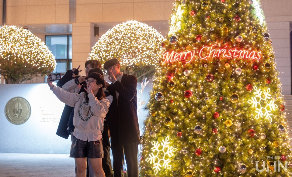 학생들이 크리스마스 트리 앞에서 사진 촬영을 하고 있다.