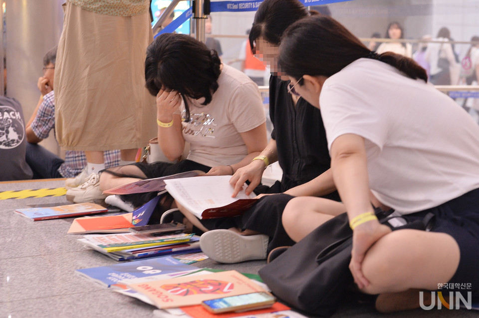 2025 수시박람회가 열린 코엑스에서 학부모와 수험생이 대학 책자를 보며 이야기를 나누고 있다. (사진=한국대학신문DB)